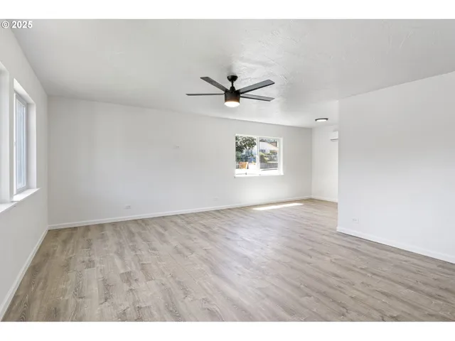 a view of an empty room with a window and wooden floor