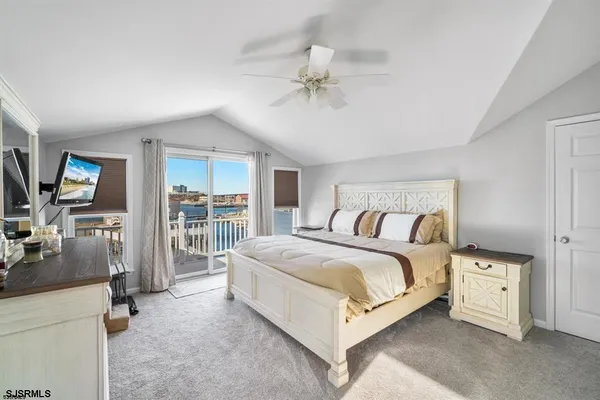 a bedroom with a large bed and a flat tv screen on dresser