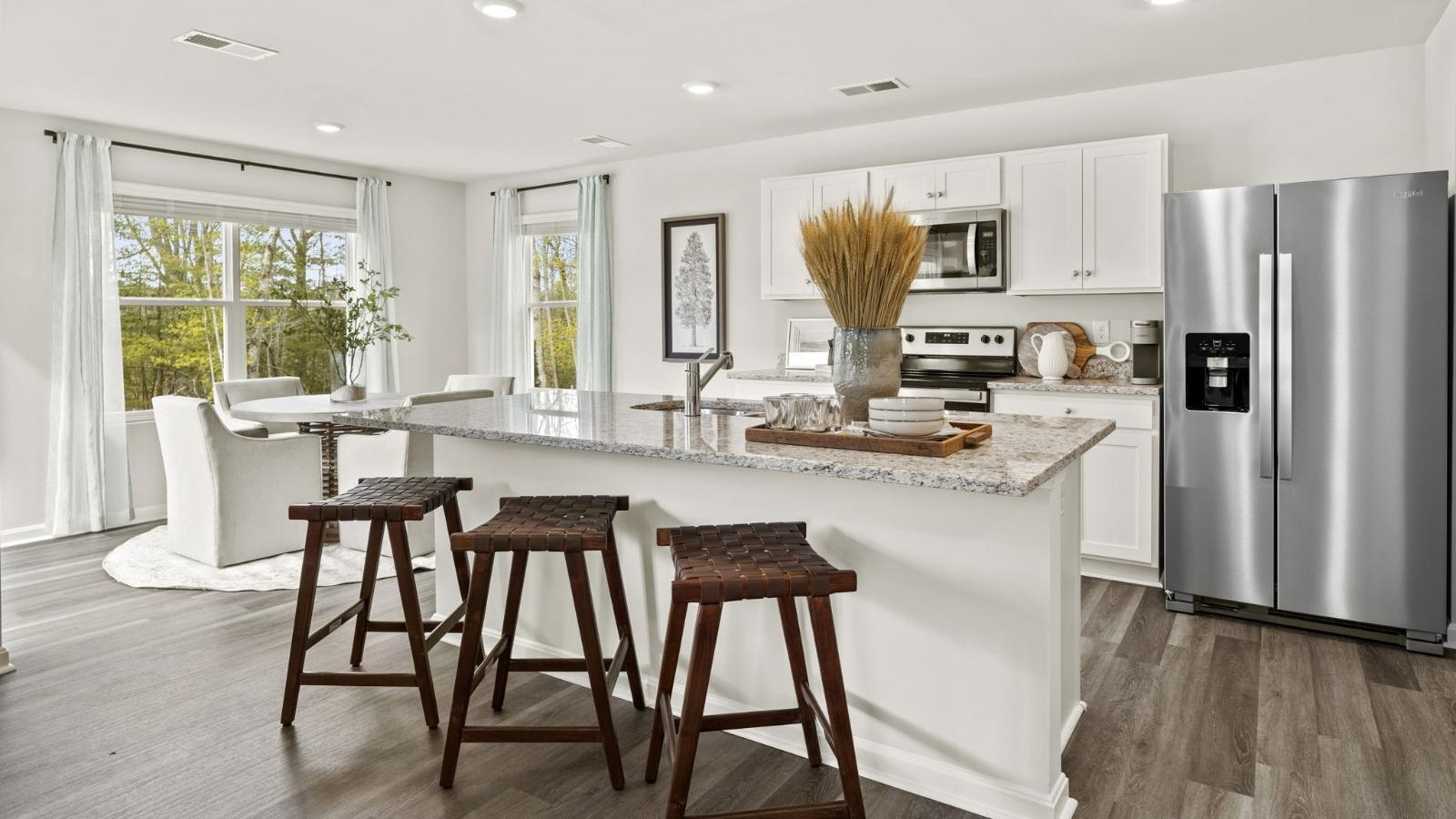 a kitchen with stainless steel appliances granite countertop dining table chairs refrigerator and microwave