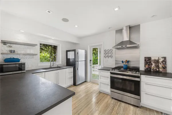 a kitchen with stainless steel appliances kitchen island granite countertop a stove a sink and a refrigerator