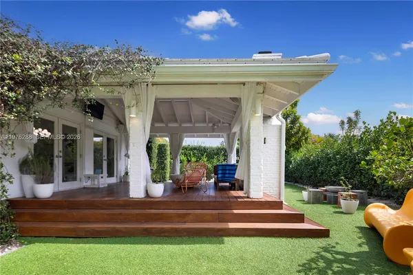 a view of a patio with couches table and chairs with potted plants and big yard