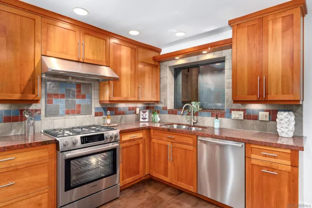 a kitchen with stainless steel appliances granite countertop a sink a stove and cabinets