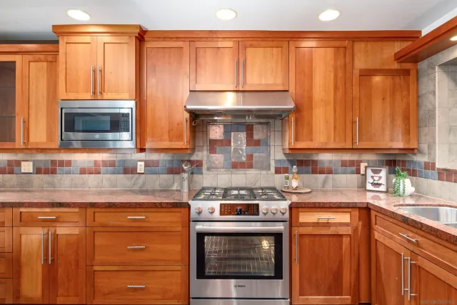 a kitchen with granite countertop a sink stainless steel appliances wooden cabinets and a counter top space