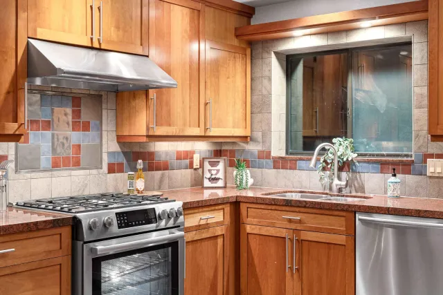 a kitchen with granite countertop a sink stainless steel appliances wooden floor and cabinets