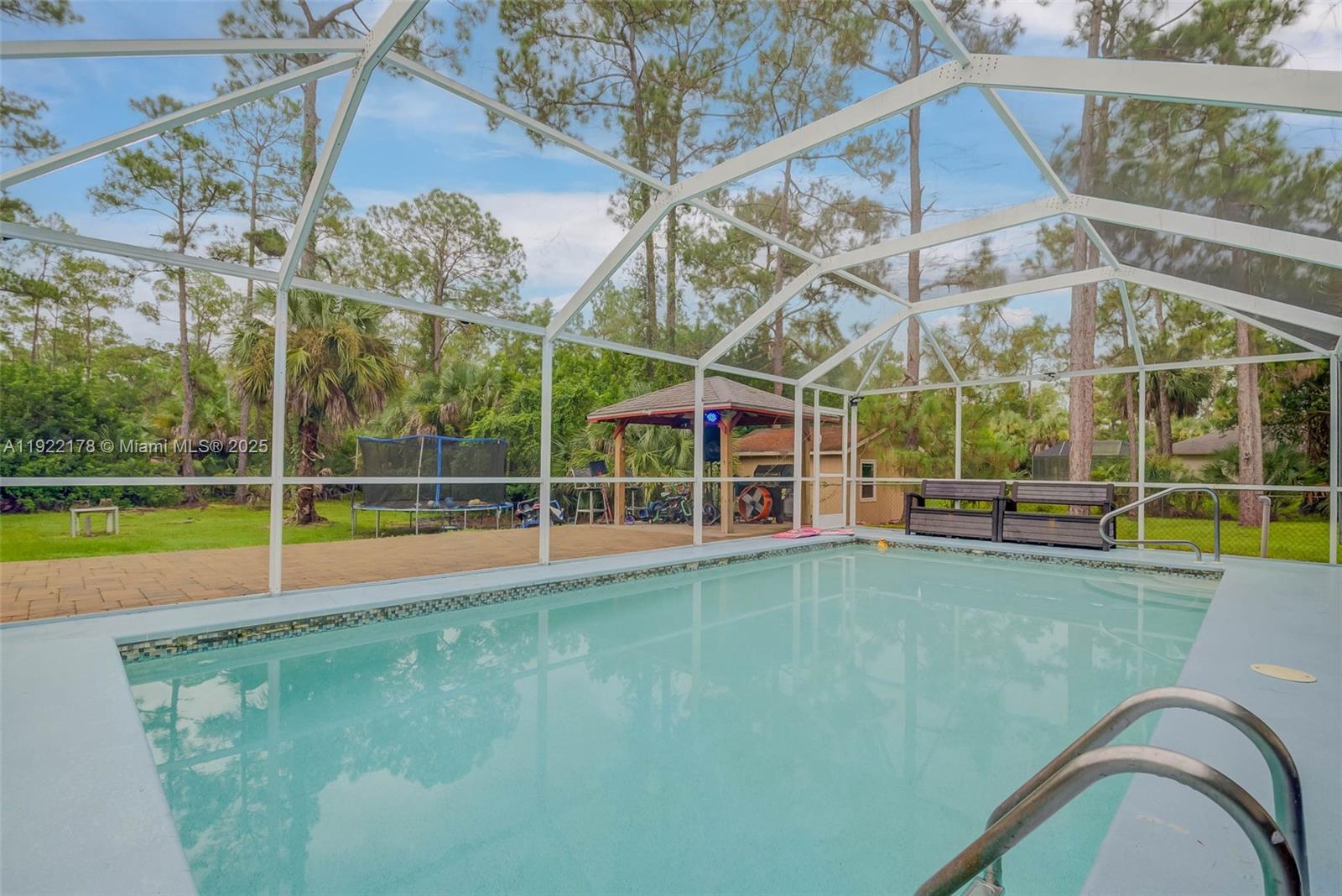 a view of a swimming pool with a yard and large trees