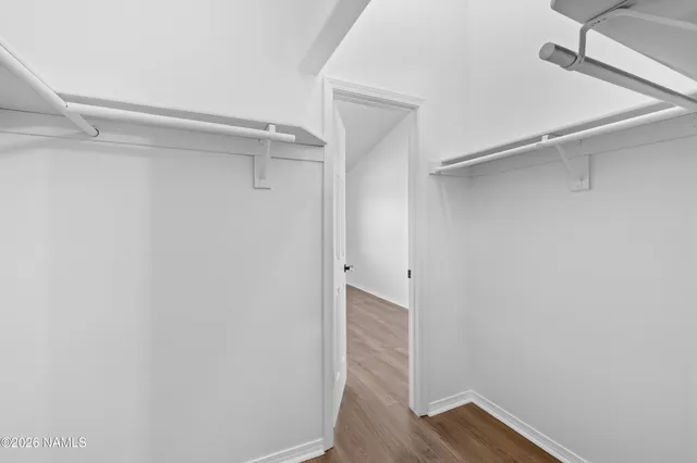 an empty room with wooden floor ceiling fan and windows