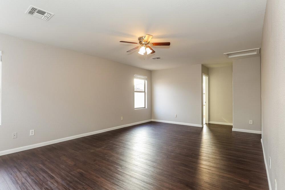 9415 Virginia Avenue Phoenix, AZ 85037 - Photo 10 of 17 an empty room with wooden floor window and ceiling fan