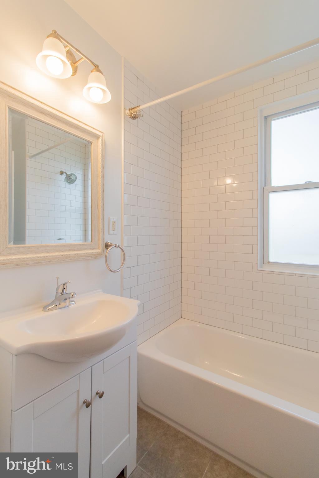 9440 Riggs Road Adelphi, MD 20783 - Photo 15 of 18 a bathroom with a bathtub shower sink and a mirror