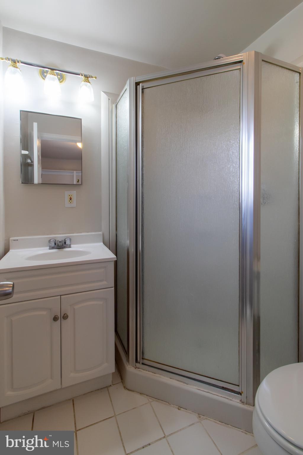 9440 Riggs Road Adelphi, MD 20783 - Photo 5 of 18 a bathroom with a shower sink and mirror
