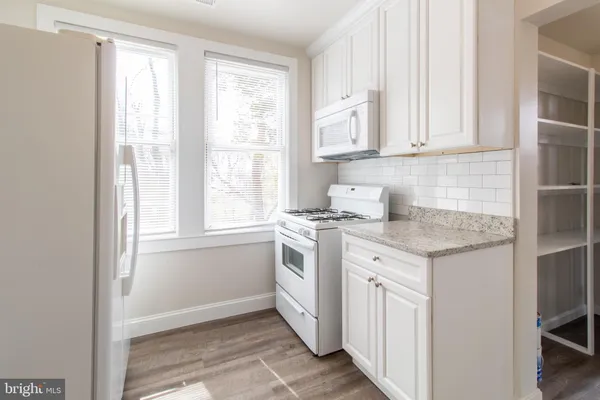a kitchen with granite countertop white cabinets and white appliances