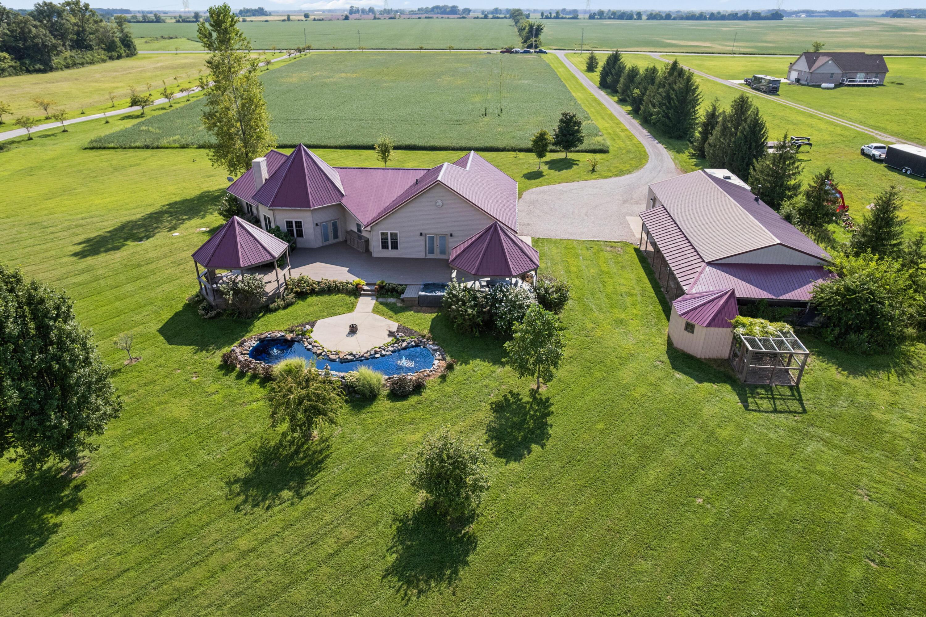 18964 London Road Circleville, OH 43113 - Photo 6 of 57 Expansive property featuring a residence with a metal roof, a detached pole barn, multiple gazebos, and a decorative pond with a central hardscaped area