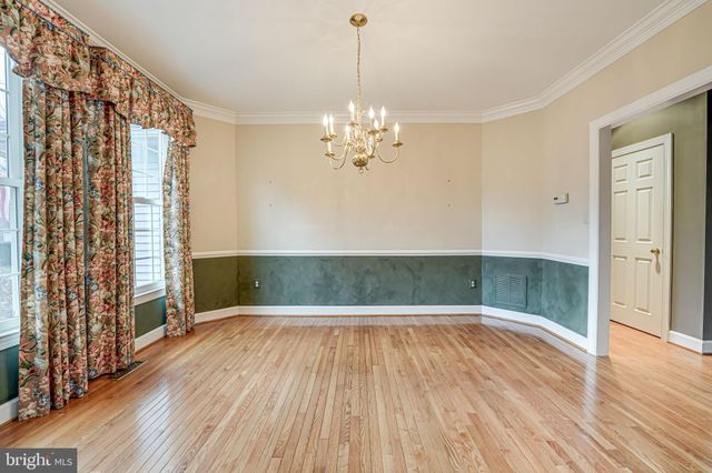 a view of a room with wooden floor chandelier and windows