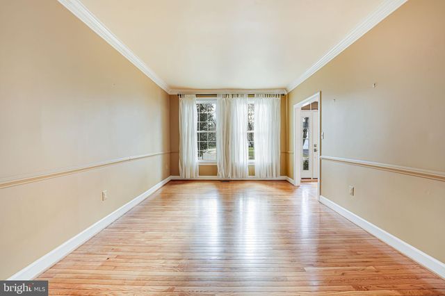 a view of an empty room with wooden floor and windows