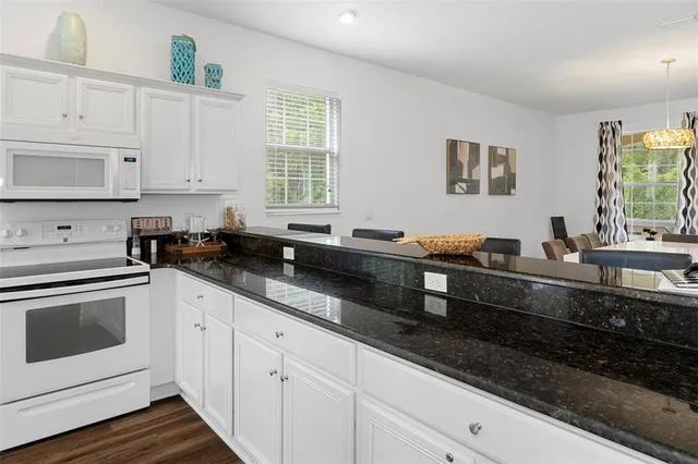 a kitchen with granite countertop white cabinets and white appliances