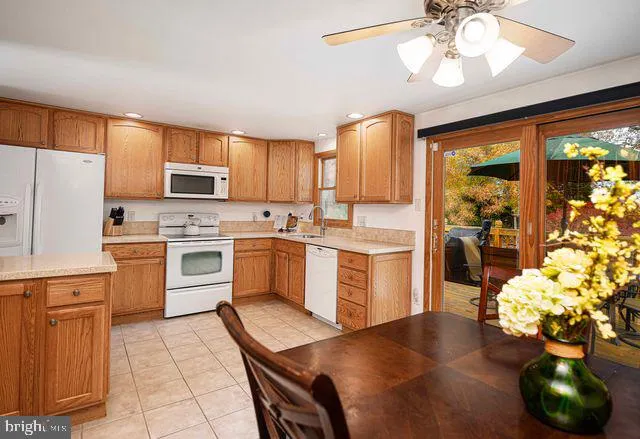 a kitchen with stainless steel appliances kitchen island granite countertop a table chairs sink and cabinets