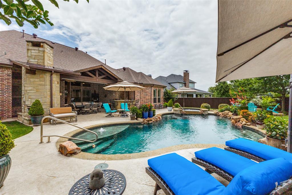 971 Elk Ridge Road Prosper, TX 75078 - Photo 25 of 29 Resort-style backyard featuring a gorgeous pool with integrated spa, stone waterfall features, plus ample space for sun bathing!