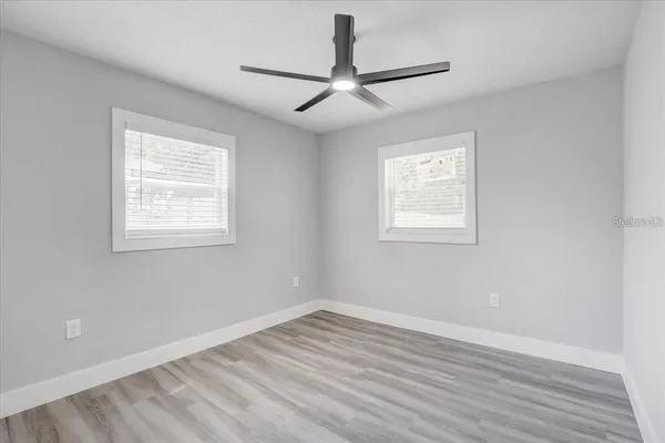 a view of empty room with wooden floor and fan