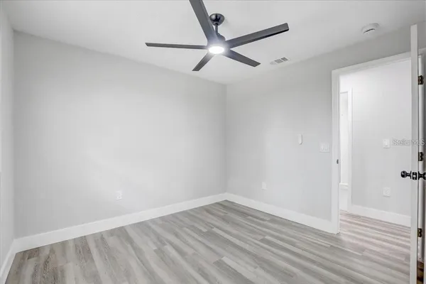 a view of a room with wooden floor and a ceiling fan