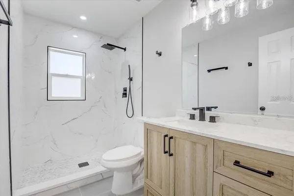 a bathroom with a granite countertop sink a toilet and shower