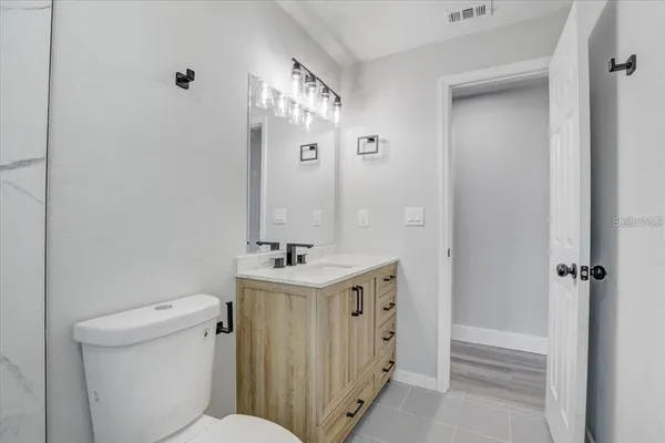 a bathroom with a granite countertop sink a toilet and shower
