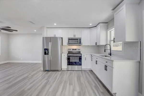 a kitchen with granite countertop a refrigerator oven a sink dishwasher and wooden cabinets with wooden floor