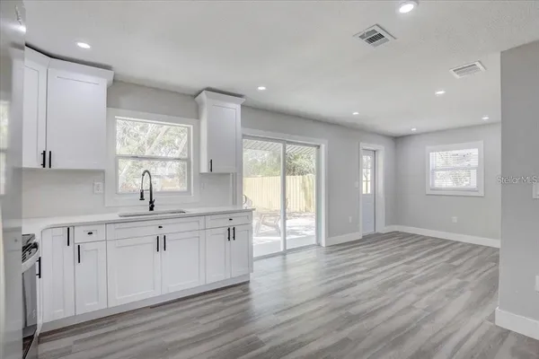 a large kitchen with cabinets wooden floor and a window