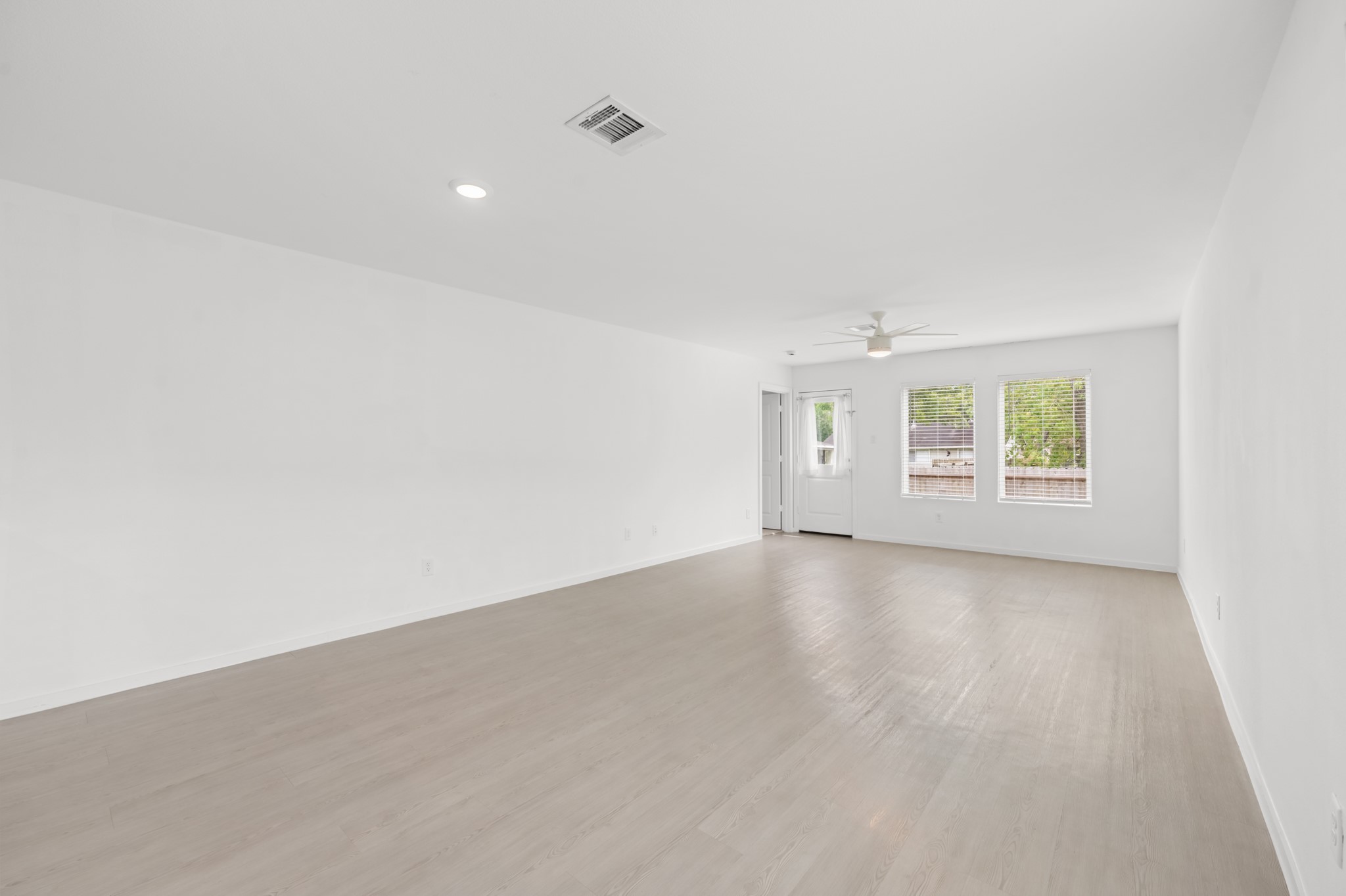 252 Houston Street Angleton, TX 77515 - Photo 11 of 49 Spacious living area features light-toned flooring, neutral finishes, and a ceiling fan, with multiple windows bringing natural light into the space.