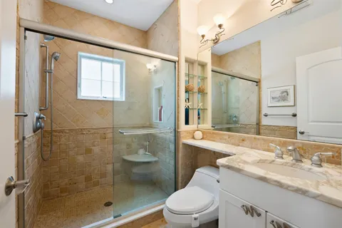a bathroom with a granite countertop sink a toilet and shower