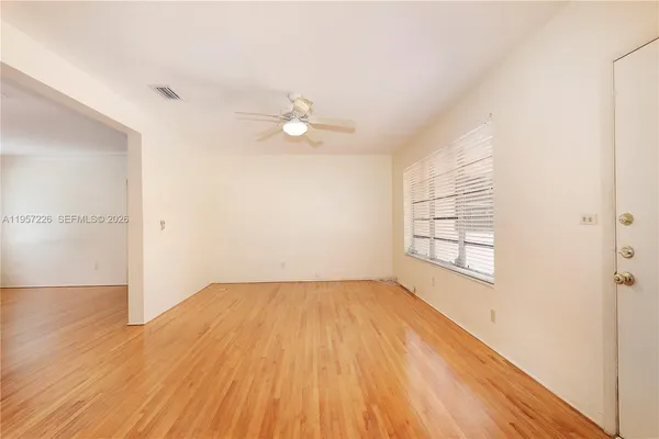 an empty room with wooden floor fan and windows