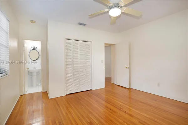 a view of an empty room with wooden floor and a ceiling fan