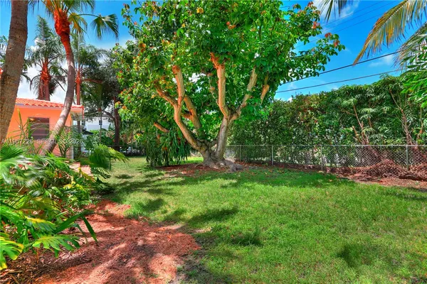 a view of backyard with table and chairs and potted plants and large trees