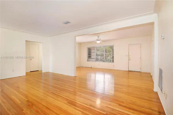 an empty room with wooden floor and windows