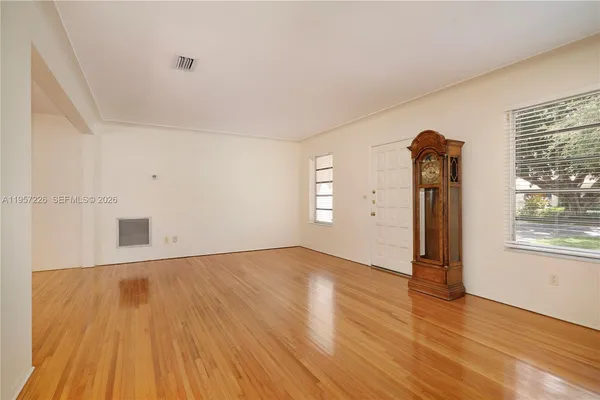 an empty room with wooden floor and windows