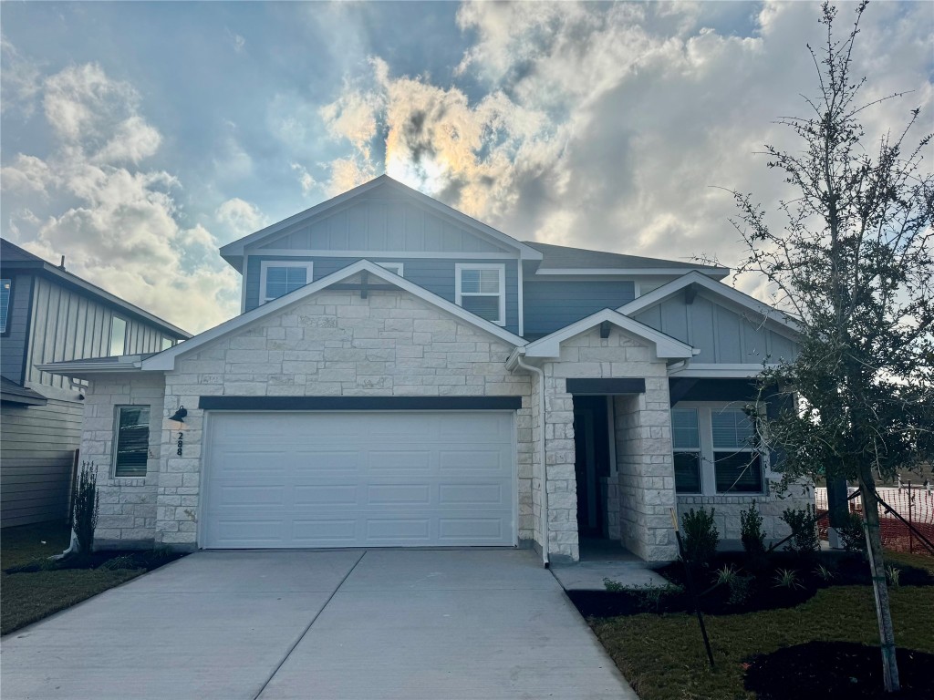 Craftsman house featuring board and batten siding, concrete driveway, stone siding, and an attached garage