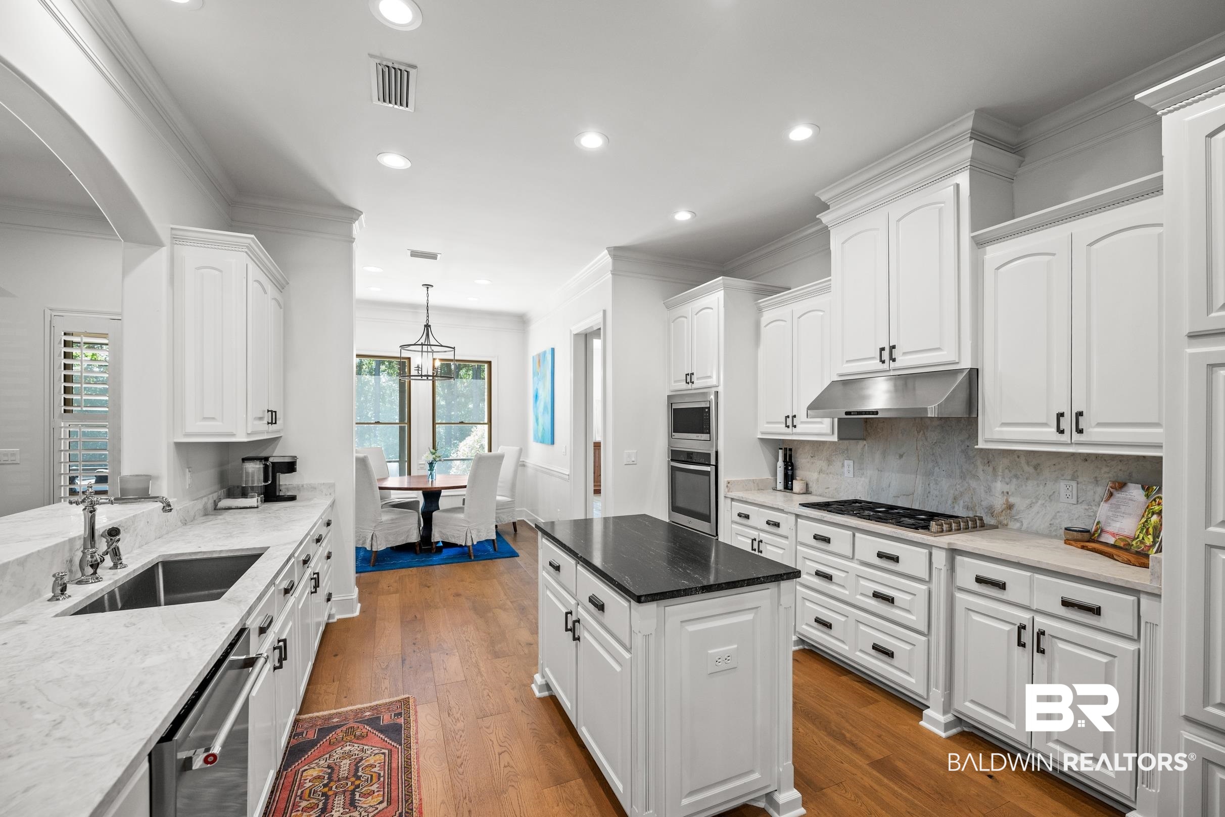 115 Sandy Ford Road Fairhope, AL 36532 - Photo 24 of 47 Kitchen with under cabinet range hood, appliances with stainless steel finishes, white cabinets, arched walkways, and backsplash