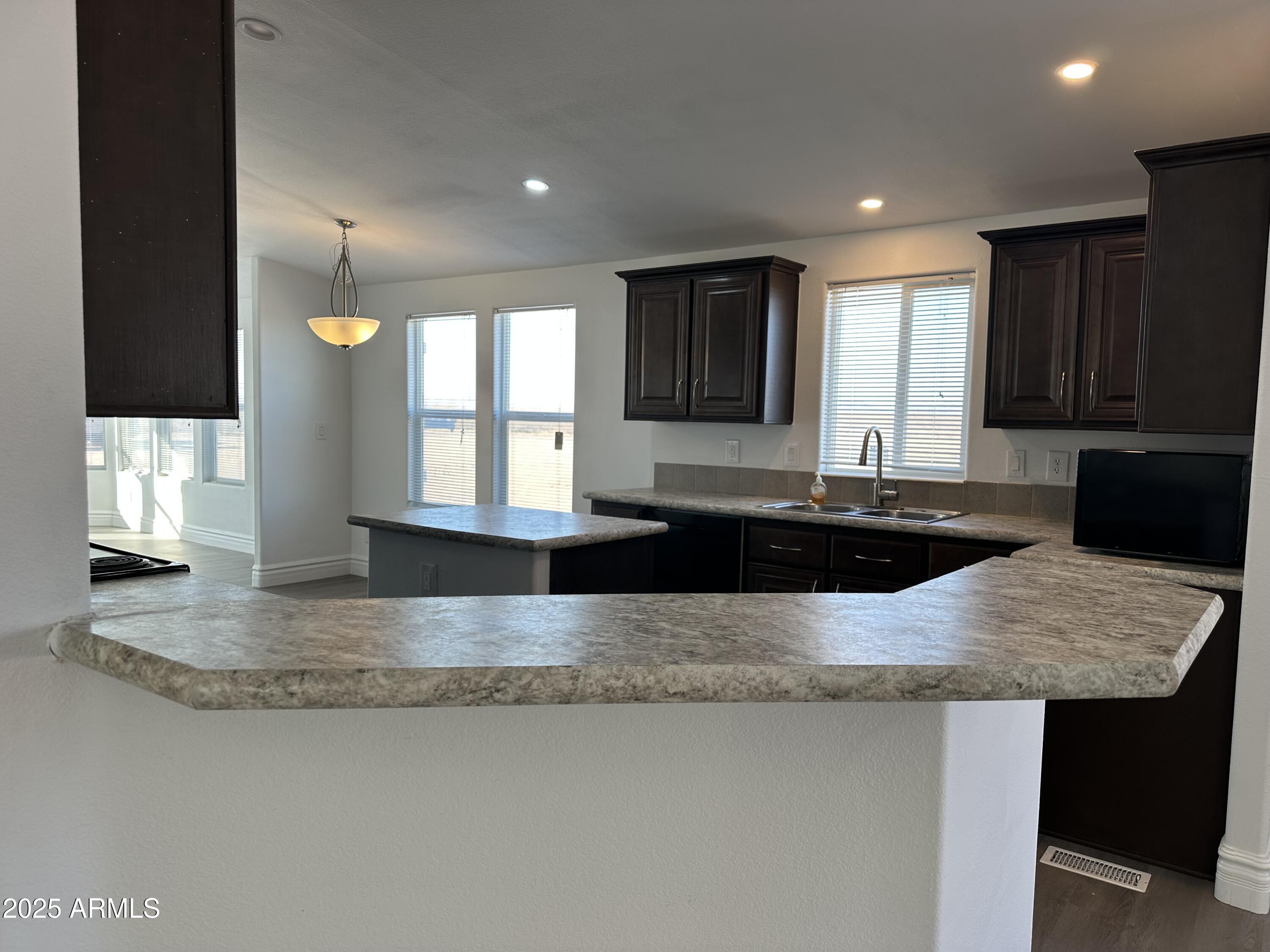 38007 West McDowell Road Tonopah, AZ 85354 - Photo 26 of 44 a kitchen with kitchen island granite countertop a sink a window and stainless steel appliances