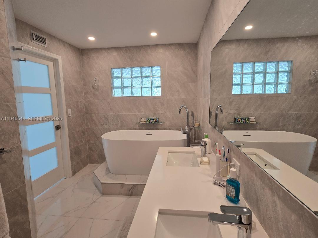 9225 Collins Avenue, Unit 1102 Surfside, FL 33154 - Photo 15 of 15 a view of a bathroom with a tub sink and mirror