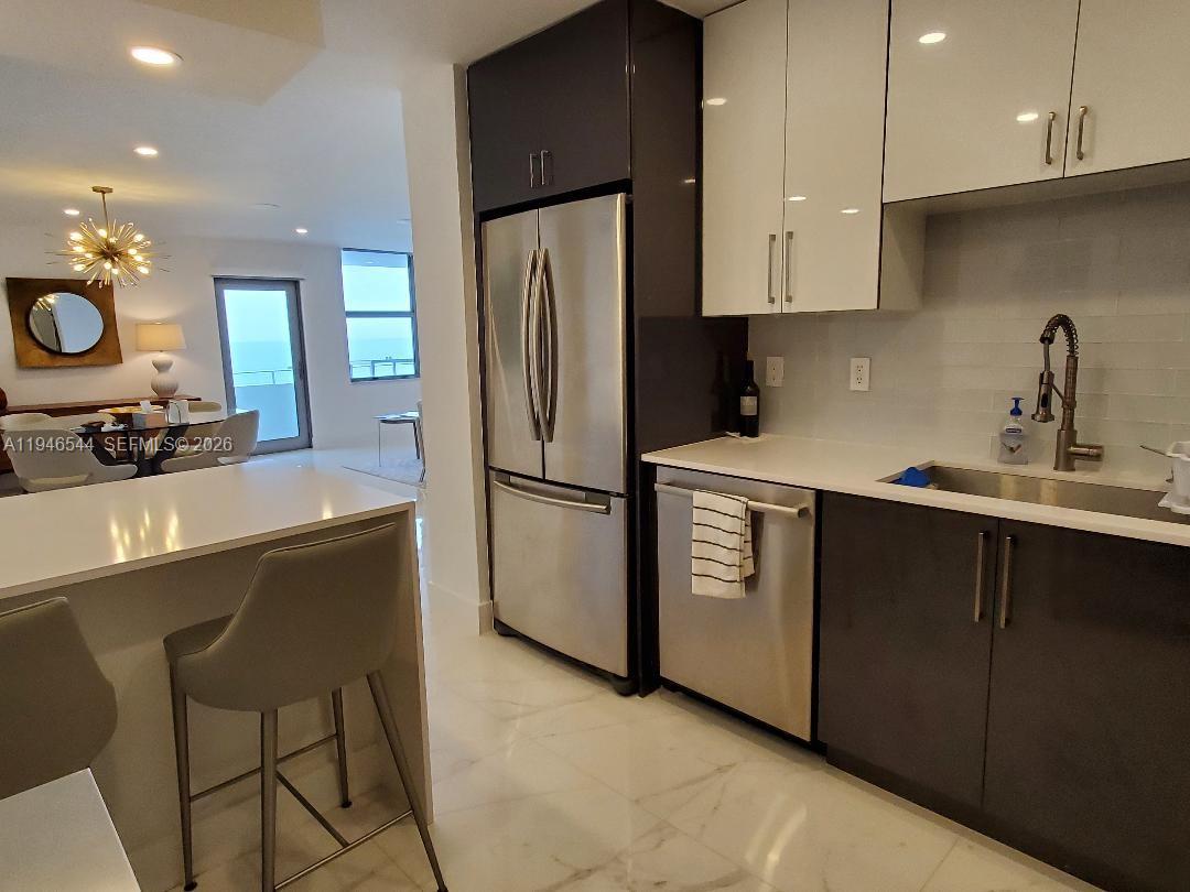 9225 Collins Avenue, Unit 1102 Surfside, FL 33154 - Photo 10 of 15 a kitchen with a refrigerator a stove a sink and a cabinets