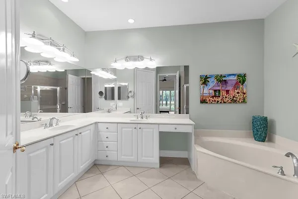 a spacious en suite bathroom with a tub double sink and glass door