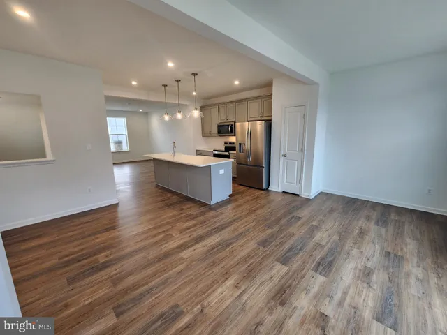 a large kitchen with stainless steel appliances a large counter top and wooden floors
