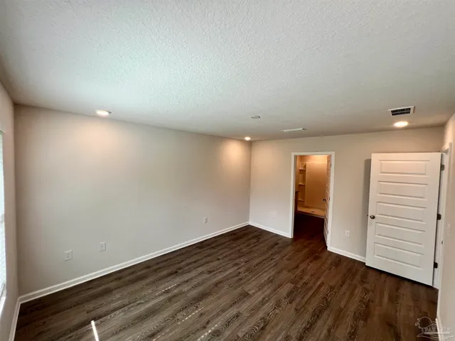 a view of an empty room with wooden floor and closet