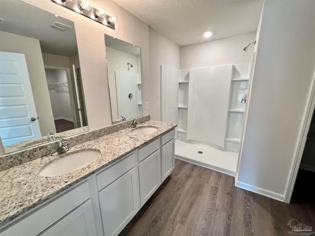 a bathroom with a granite countertop double vanity sink and mirror