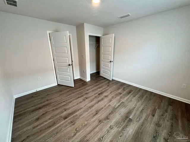 an empty room with wooden floor and closet