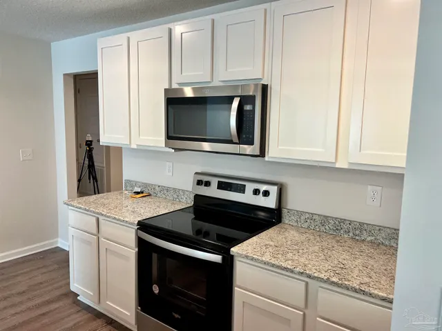 a kitchen with stainless steel appliances granite countertop a stove microwave and sink