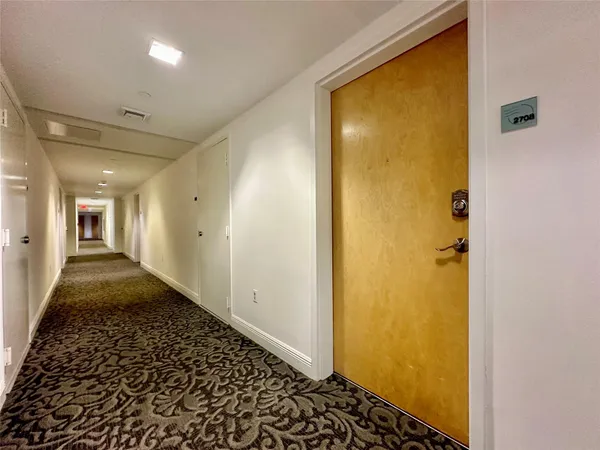 a view of a hallway with a door and wooden floor