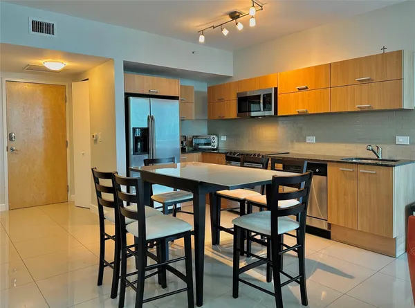 a dining room with stainless steel appliances a table and chairs