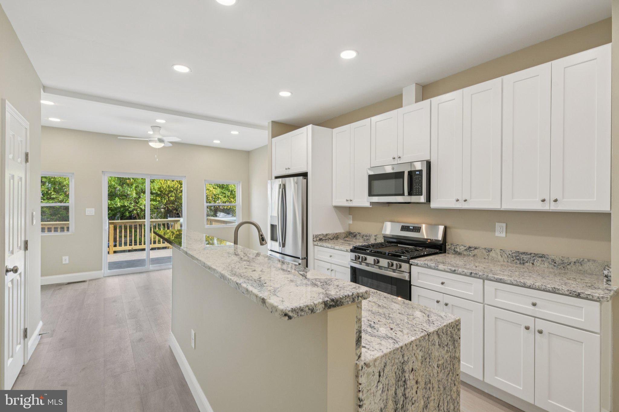 729 Madison Street Northwest Washington, DC 20011 - Photo 15 of 59 a kitchen with granite countertop a stove a sink a microwave a dining table and chairs