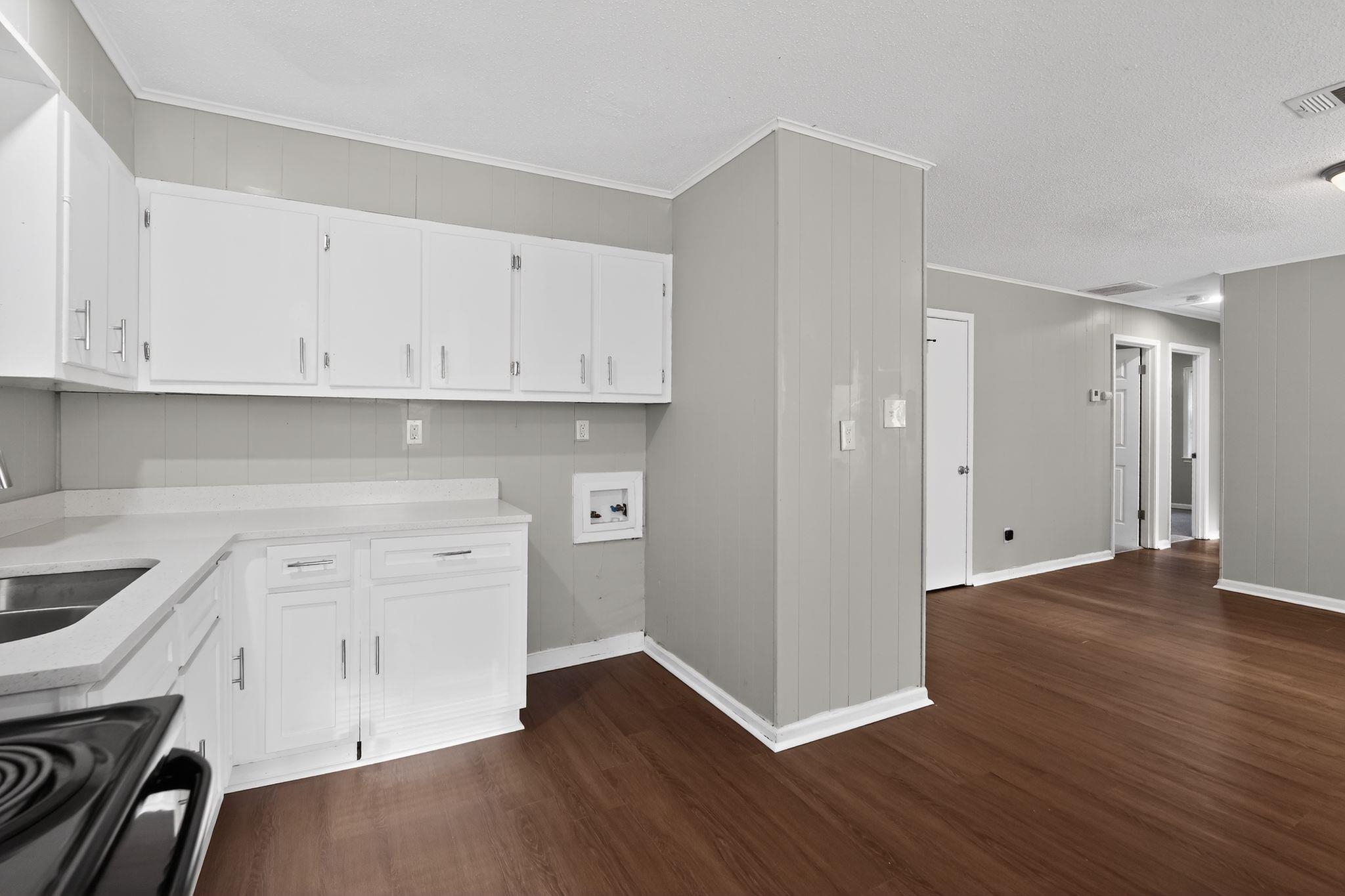4686 Gill Road Memphis, TN 38109 - Photo 19 of 32 Kitchen area featuring white cabinetry, light countertops, a stainless steel sink, and wood-finish flooring