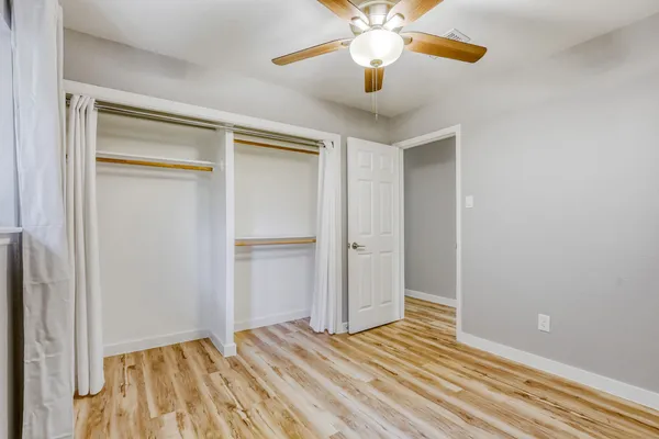 a view of a room with wooden floor and a ceiling fan