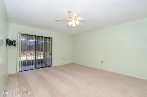 an empty room with a ceiling fan and window